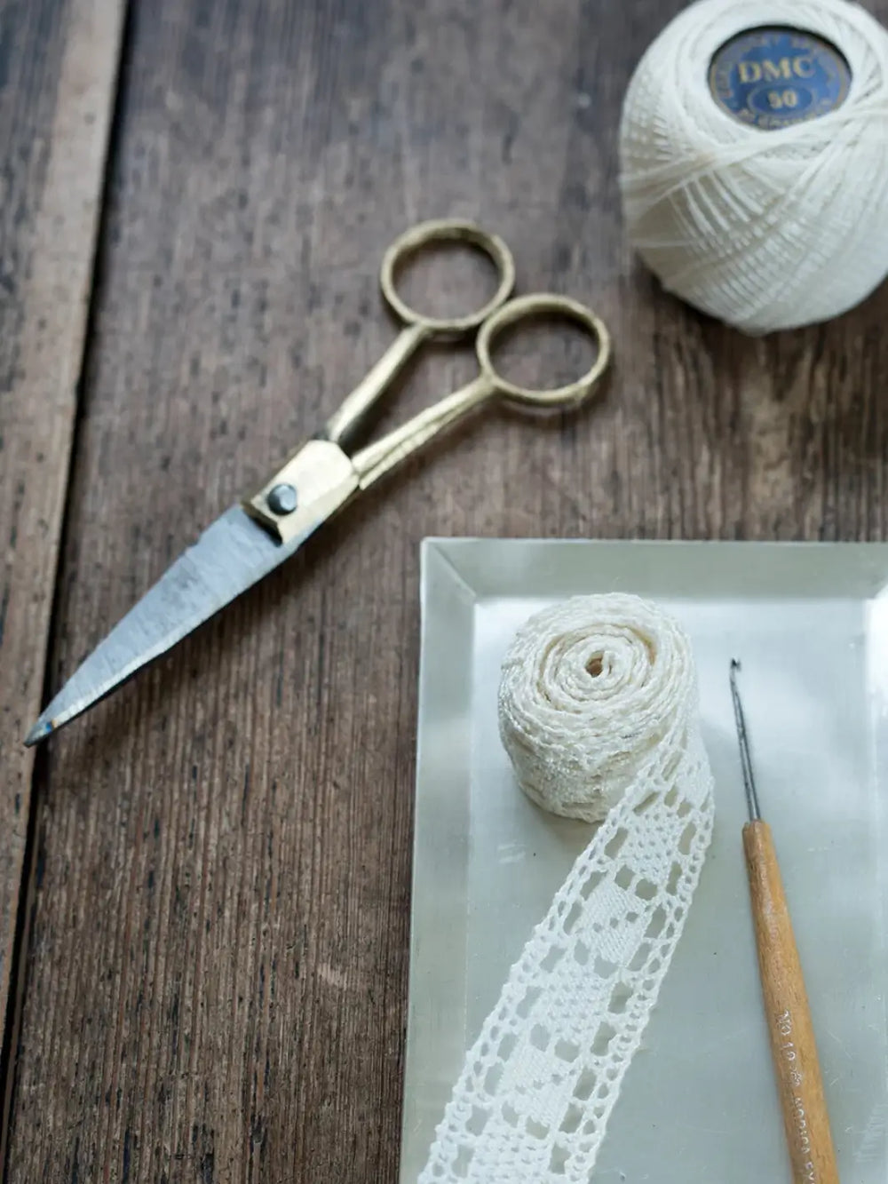Brass Handle Scissors Small from Fog Linen Work resting on a rustic wooden table alongside crochet supplies | Twentyseven Toronto