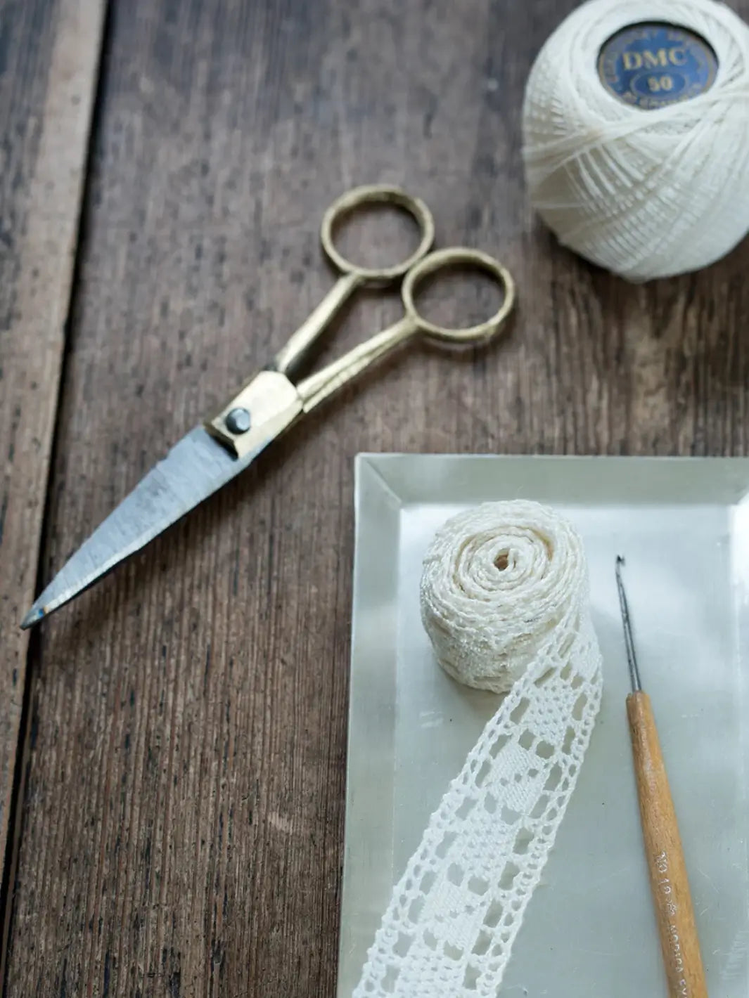 Brass Handle Scissors Small from Fog Linen Work resting on a rustic wooden table alongside crochet supplies | Twentyseven Toronto