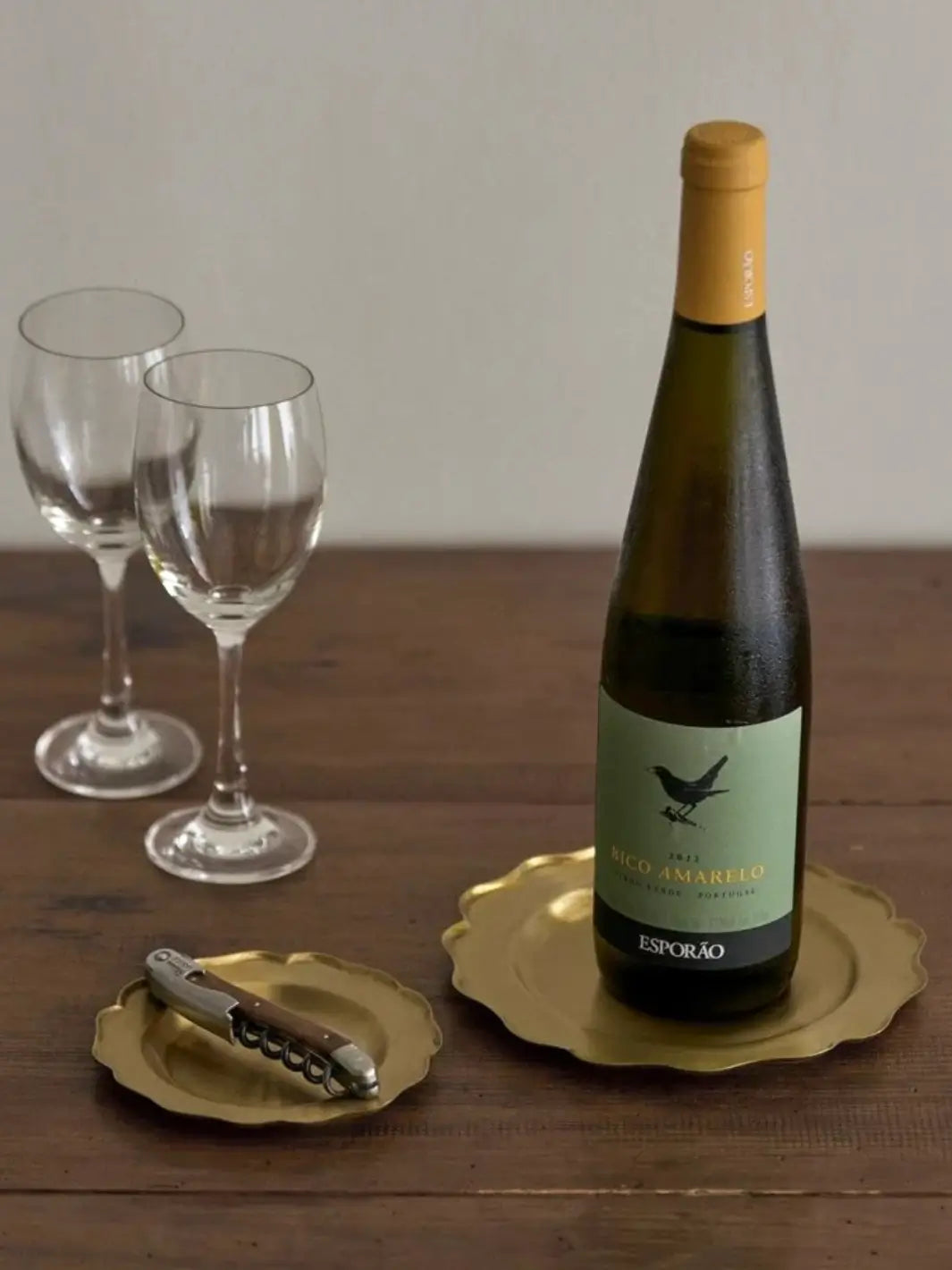 Fog Linen Work Brass Ruffle Edge Tray Small is used as a functional coaster for a wooden-handled corkscrew on a rustic dining table next to a bottle of wine | Twentyseven Toronto