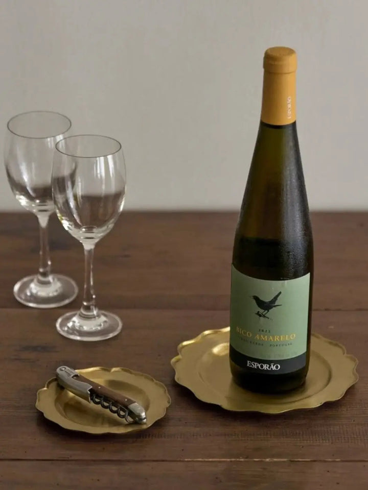 Fog Linen Work Brass Ruffle Edge Tray Small is used as a functional coaster for a wooden-handled corkscrew on a rustic dining table next to a bottle of wine | Twentyseven Toronto