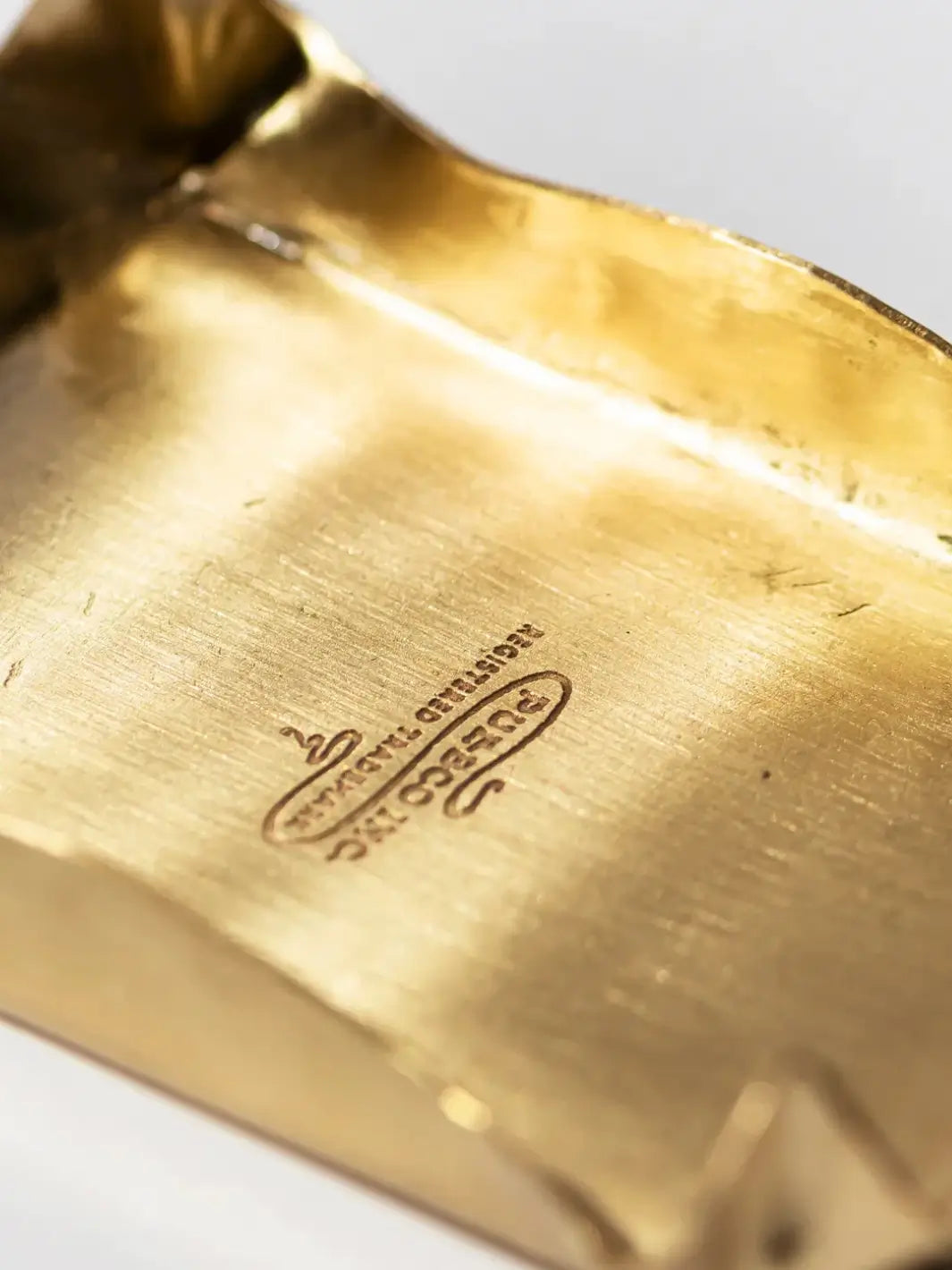 Close-up shot highlights the brushed metallic finish and engraved logo emblem inside the Brass Small Tray from Puebco | Twentyseven Toronto