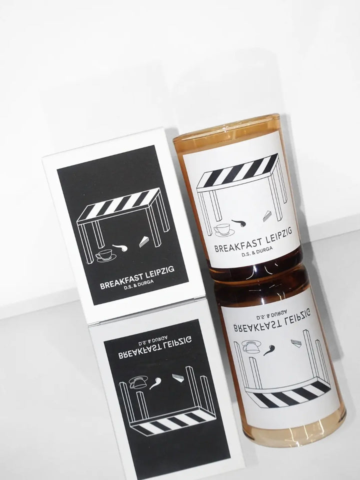 DS&Durga candle in a glass jar labeled 'Breakfast Leipzig' with packaging featuring cafe illustrations on a reflective surface | Twentyseven Toronto