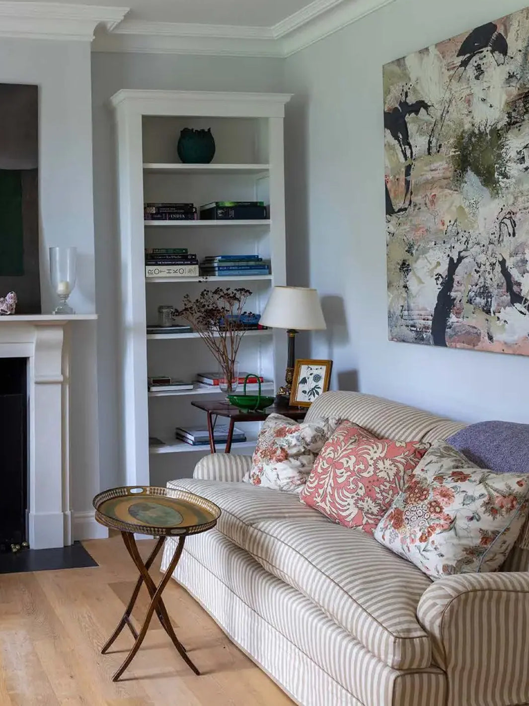 Living room featured in British Designers at Home, with a striped sofa, floral cushions, built-in shelving and  | Twentysevne Toronto