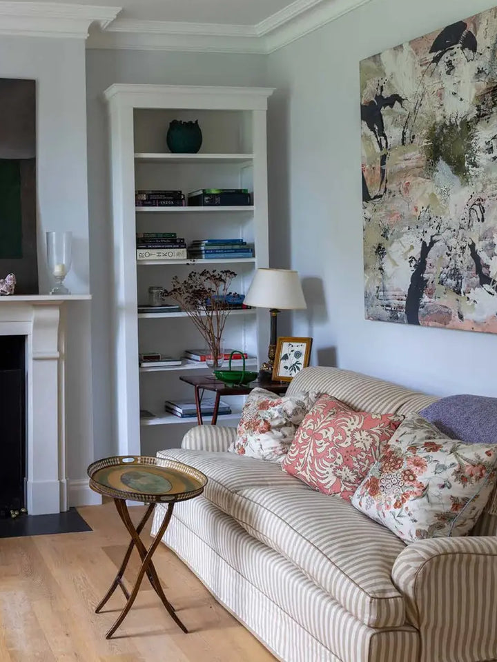 Living room featured in British Designers at Home, with a striped sofa, floral cushions, built-in shelving and  | Twentysevne Toronto