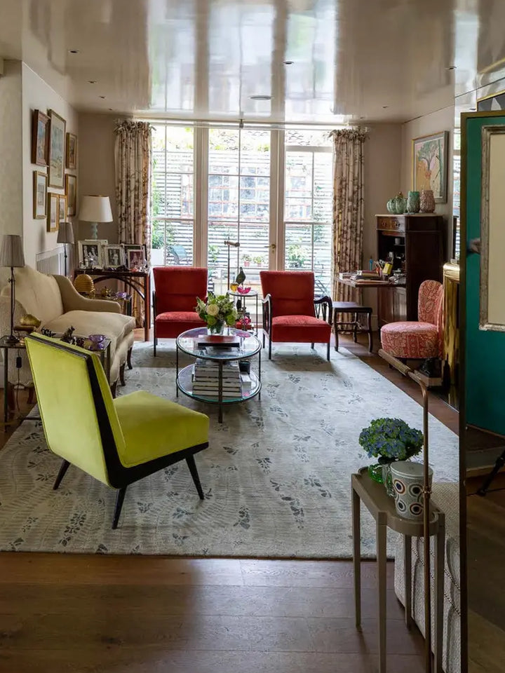 Colourful living room featured in British Designers at Home, with red and green accent chairs, layered artwork and vintage furnishings | Twentyseven Toronto