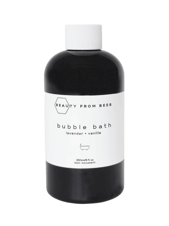 Black bottle of bubble bath in Lavender + Vanilla from Beauty from Bees with a white label on a transparent background | Twentyseven Toronto