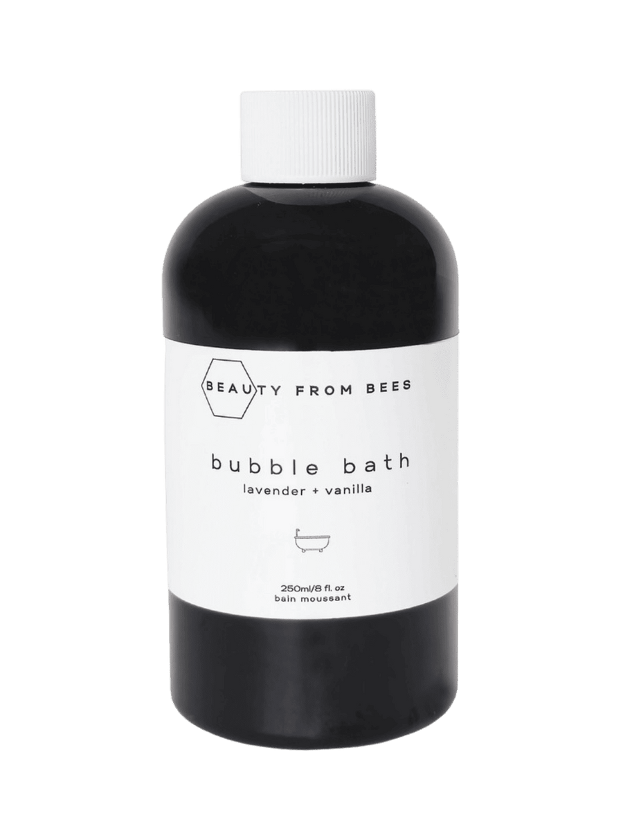 Black bottle of bubble bath in Lavender + Vanilla from Beauty from Bees with a white label on a transparent background | Twentyseven Toronto