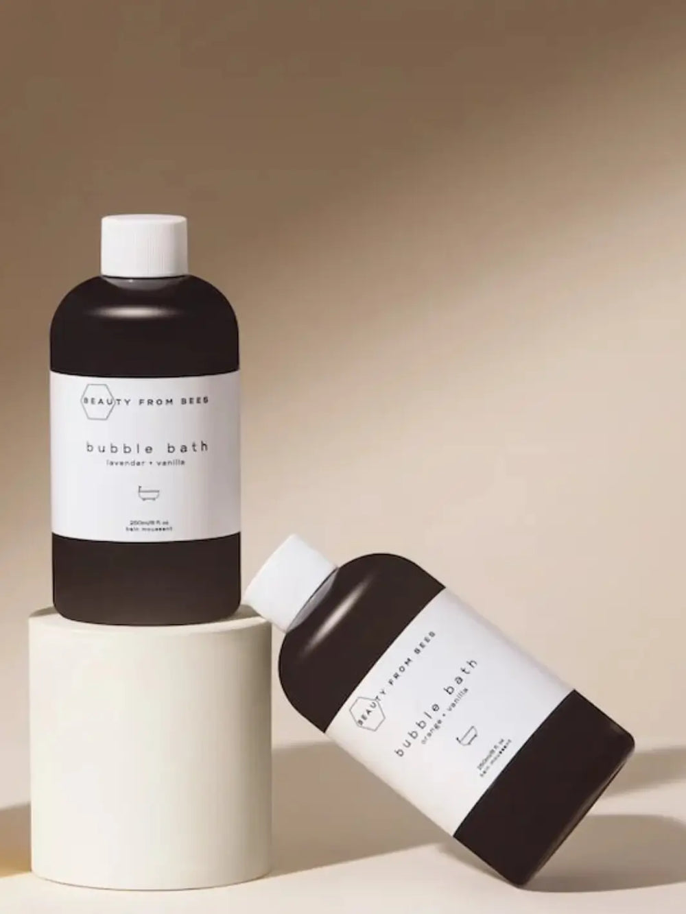 Two bottles of bubble bath from Beauty from Bees with a beige background | Twentyseven Toronto