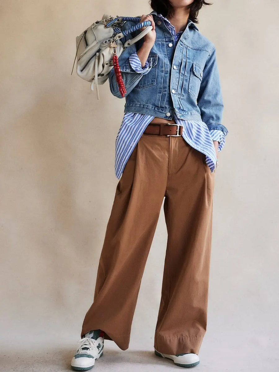 A model poses from the waist down wearing the wide-leg Free People Buckle Back Trousers - Tobacco Combo styled with a denim jacket and striped button-down shirt | Twentyseven Toronto