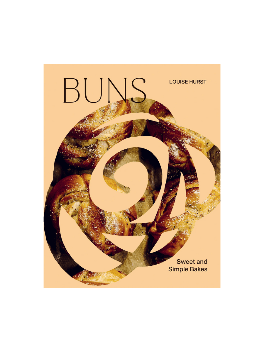 Front cover of the cookbook BUNS: Sweet and Simple Bakes by Louise Hurst, featuring a peach-colored background with a large, central cutout in the shape of a stylized rose | Twentyseven Toronto