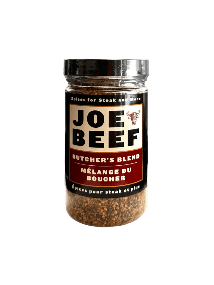A clear glass jar filled with spice mix features a black and white label for Butcher's Blend Joe Beef seasoning with a red banner that reads "Mélange du Boucher" | Twentyseven Toronto