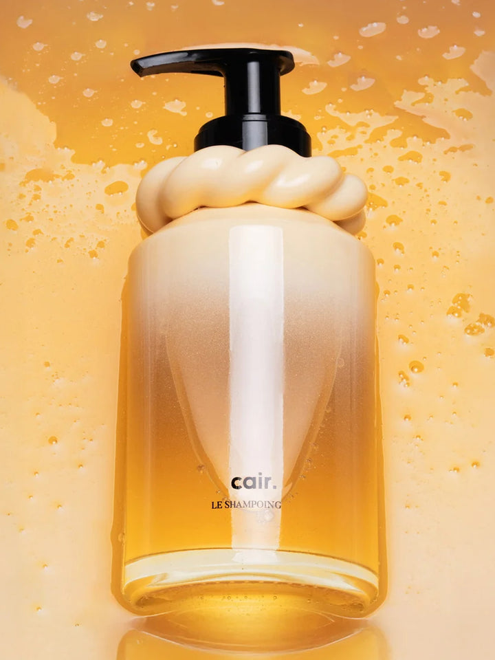 1. La Bonne Brosse Cair Shampoo in a yellow glass pump bottle surrounded by water droplets | Twentyseven Toronto