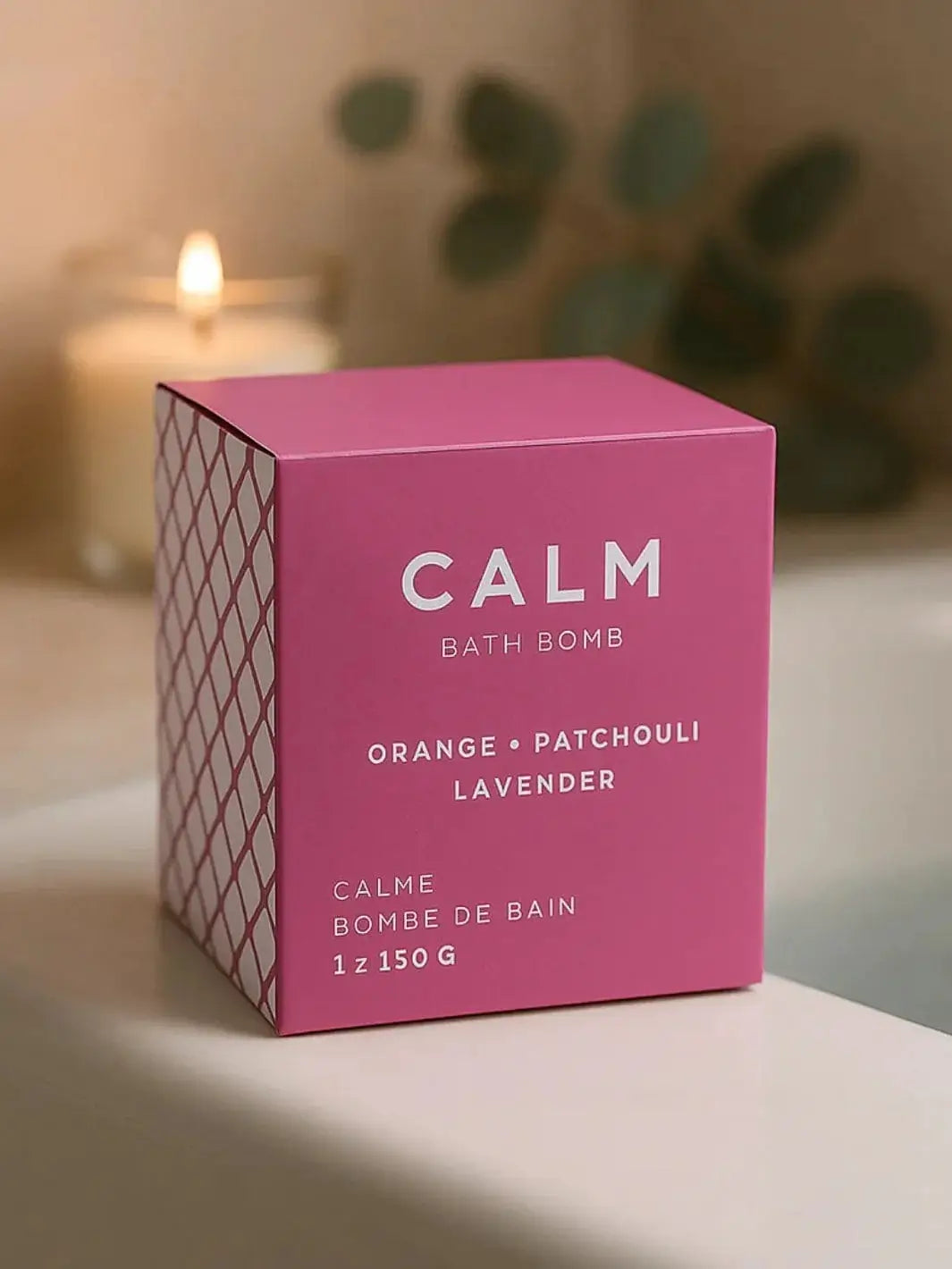 The pink rectangular box for the Bare Skin Bar CALM Bath Bomb rests on the edge of a bathtub with a lit candle glowing in the background | Twentyseven Toronto