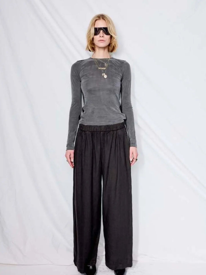 A model poses in front of a white backdrop wearing a grey long-sleeve top styled with the wide-leg, relaxed-fit Jungmaven Cambria Pant - Black | Twentyseven Toronto