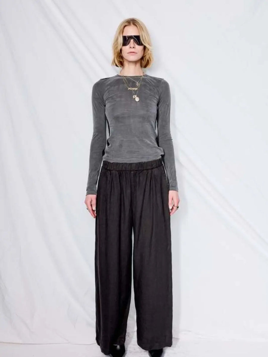 A model poses in front of a white backdrop wearing a grey long-sleeve top styled with the wide-leg, relaxed-fit Jungmaven Cambria Pant - Black | Twentyseven Toronto