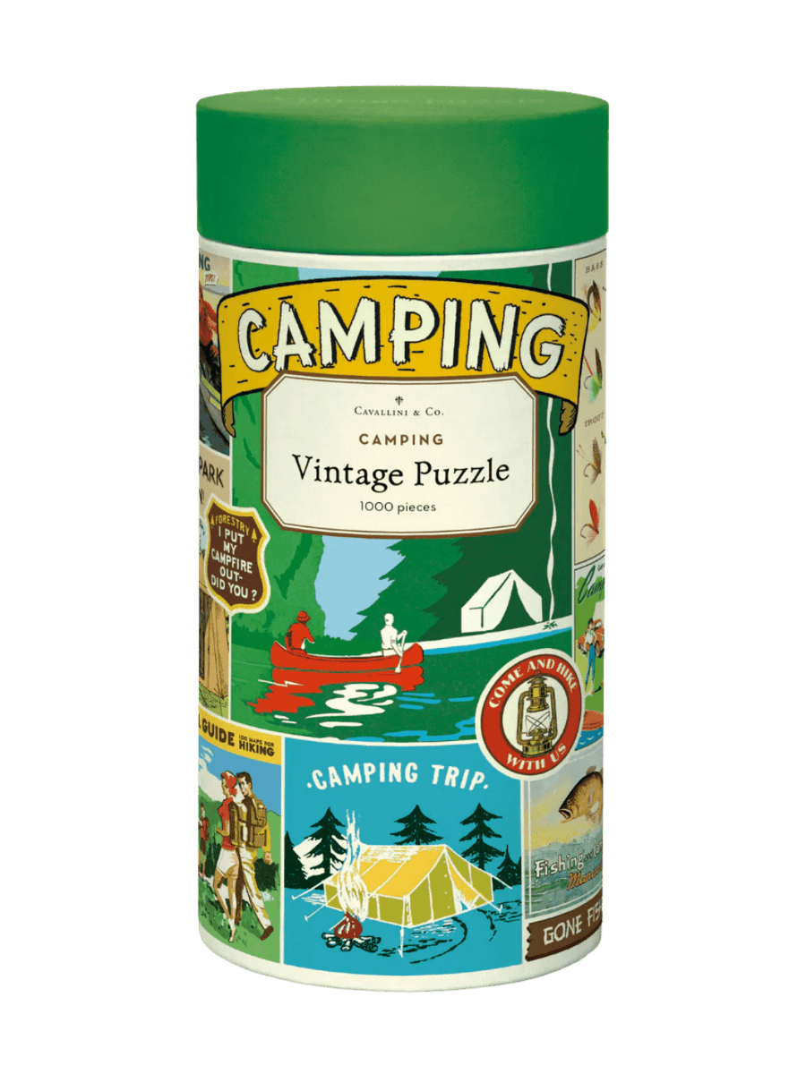Cylindrical paper tube for the Cavallini Paper & Co Camping 1000 Piece Puzzle with a green cap, highlighting a central title card above an illustration of a red canoe on a river | Twentyseven Toronto