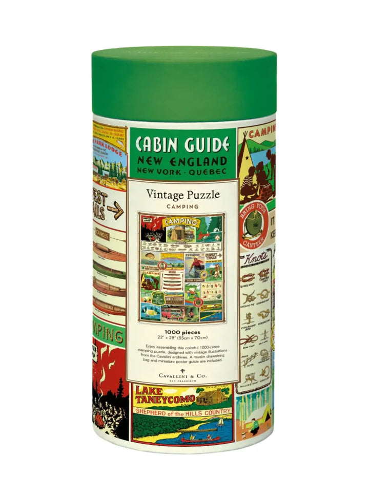 Cylindrical cardboard packaging for the Cavallini Paper & Co Camping 1000 Piece Puzzle, showcasing a bright green cap and a retro wilderness collage label featuring canoes and campfires against a white background | Twentyseven Toronto