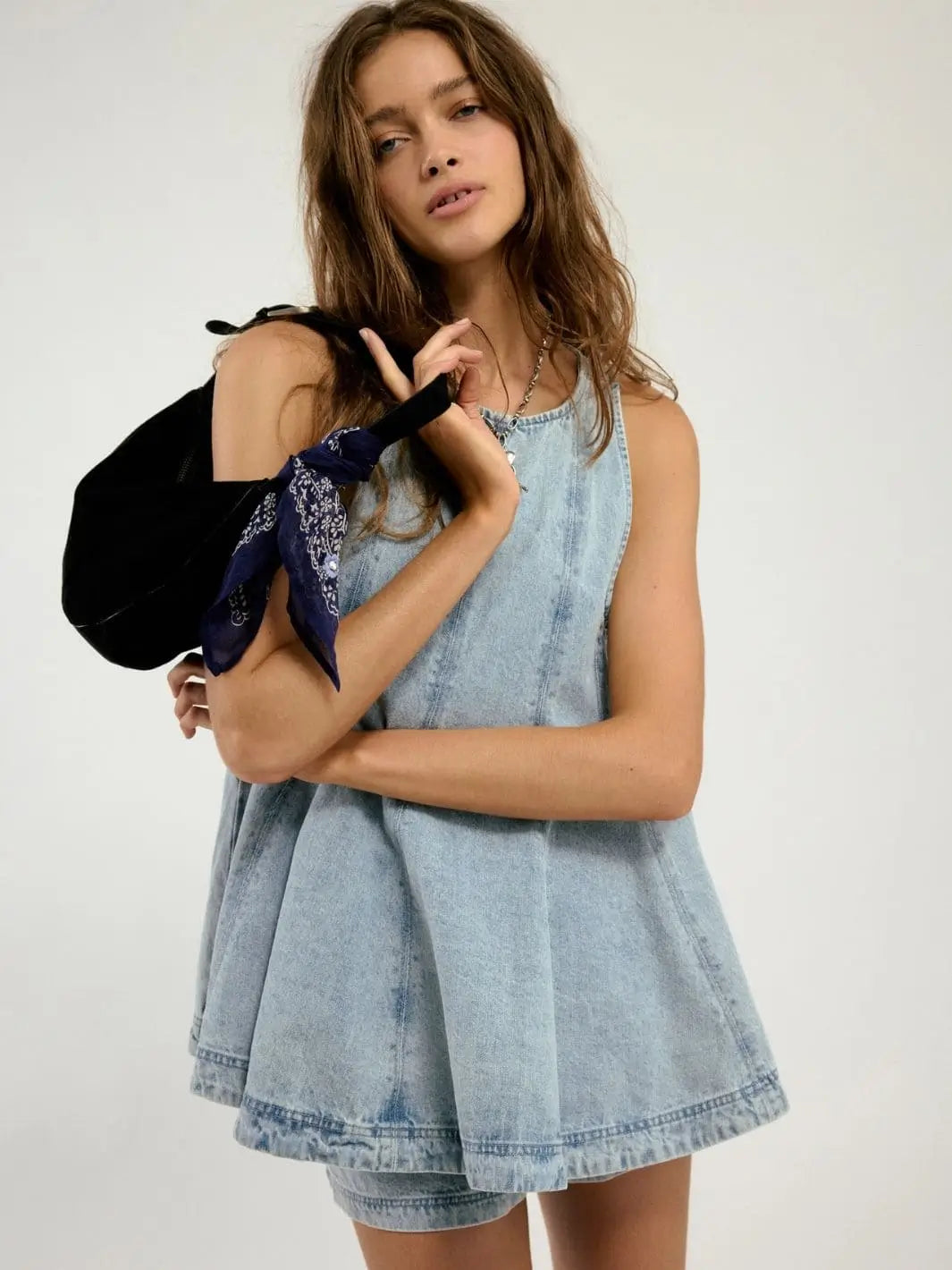 A medium close-up shot emphasizes the model holding a black shoulder bag with a blue bandana accent alongside the Free People Cassius Denim Set in Bleachout | Twentyseven Toronto