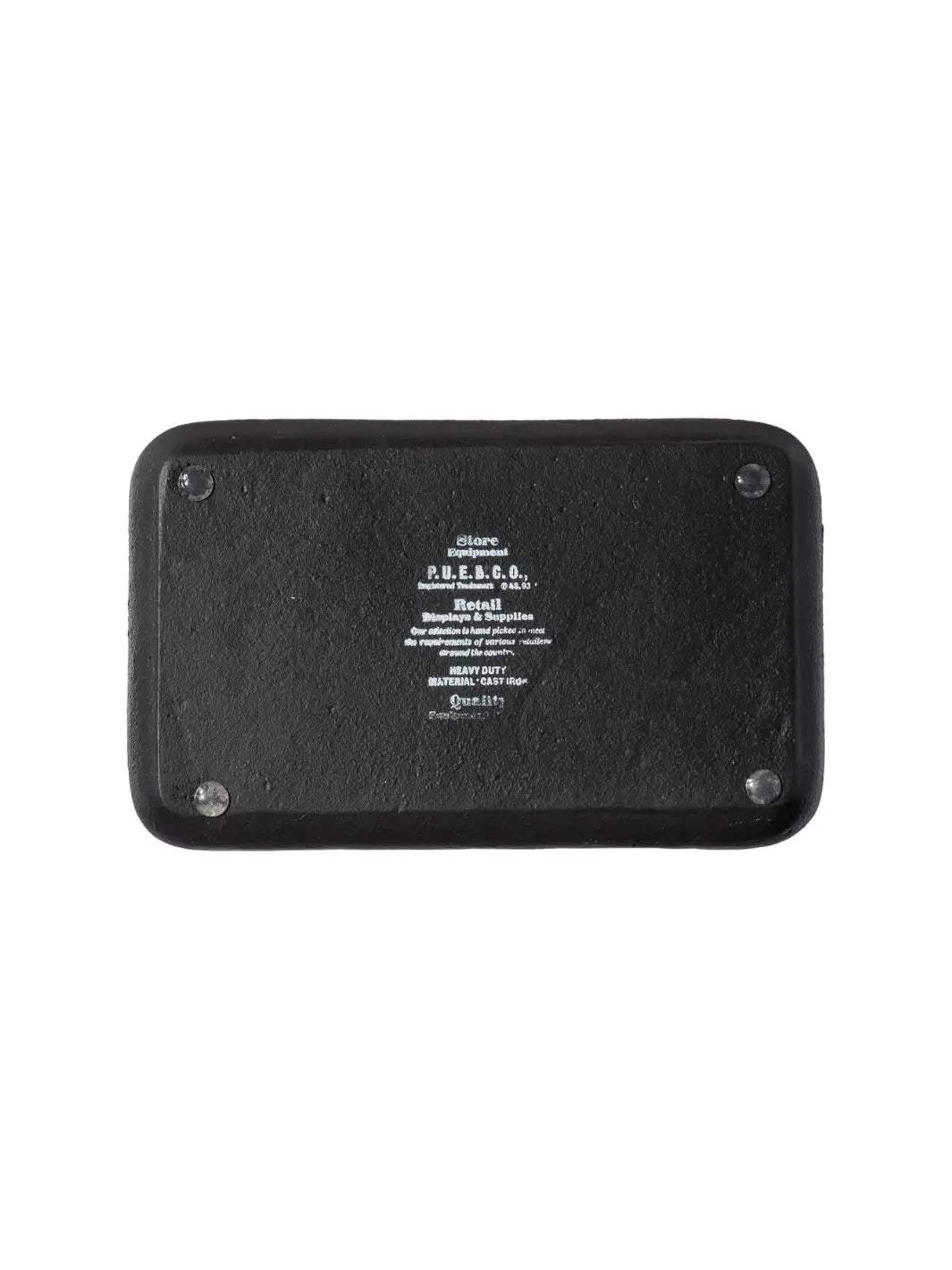 The underside of the Cast Iron Tray - Black from Puebco detailed with embossed branding text reading "P.U.E.B.C.O. Heavy Duty Material Cast Iron" and four small, protective rubber feet on the corners | Twentyseven Toronto