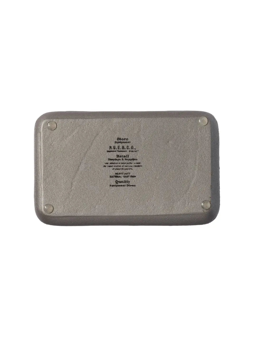The underside of the Cast Iron Tray - Natural from Puebco detailed with embossed branding text reading "P.U.E.B.C.O. Heavy Duty Material Cast Iron" and four small, protective rubber feet on the corners | Twentyseven Toronto