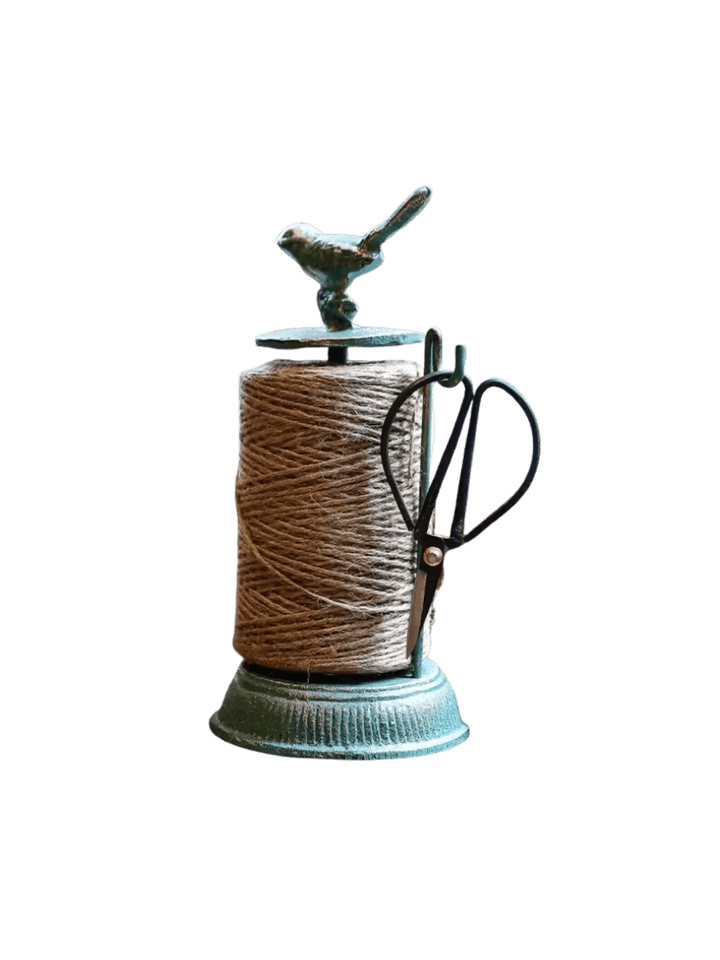 A rustic turquoise Cast Iron Twine Dispenser with Bird Accent from Laura Hooper Design House features a spool of natural jute twine and a side-mounted hook holding small black crafting scissors | Twentyseven Toronto