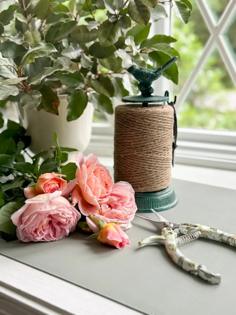 Side view of the Cast Iron Twine Dispenser with Bird Accent from Laura Hooper Design House highlights its ornate, antique-inspired base and the small bird figure that serves as a handle for the center rod | Twentyseven Toronto