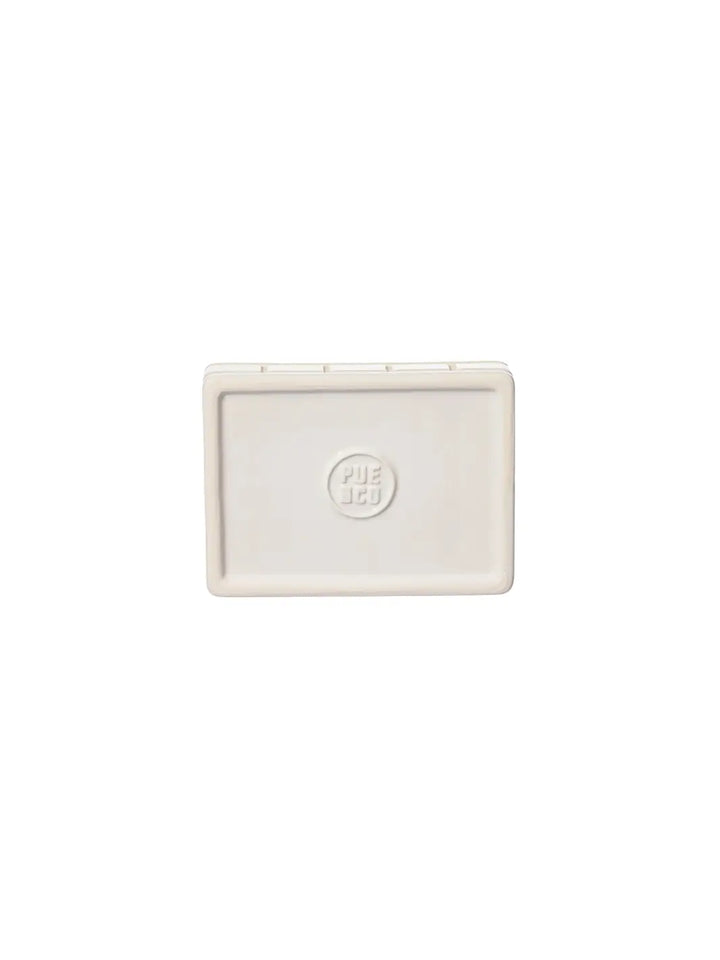 A top-down view showing the smooth, clean underside of the white Ceramic Bath Ensemble / Soap Dish from Puebco, featuring a circular debossed brand logo in the centre | Twentyseven Toronto