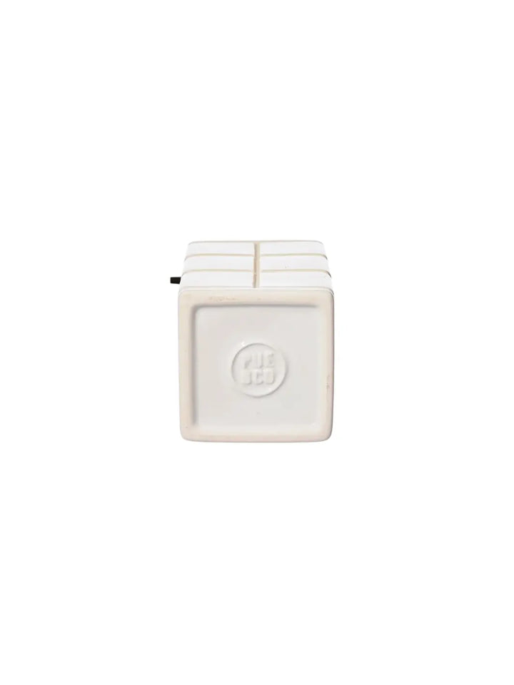 The square bottom base of the white Ceramic Bath Ensemble / Soap Dispenser from Puebco, featuring its clean ceramic finish and a central debossed round brand stamp | Twentyseven Toronto