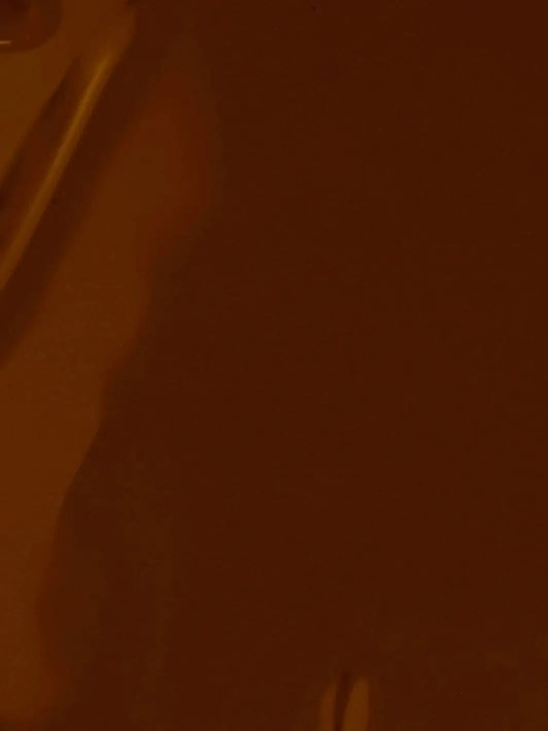 A full-frame texture shot showing the smooth, glossy, liquid surface of the deep warm brown BKIND Nail Polish in Chai formula | Twentyseven Toronto