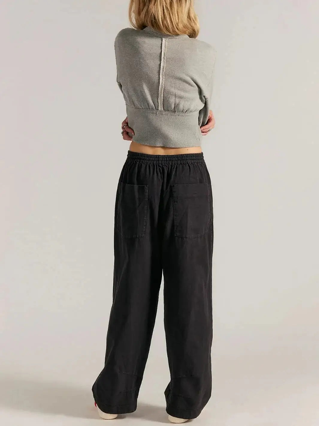 A full-length rear view shows a model showcasing the straight-leg drape and large back patch pockets of the Free People Chambers Laidback Pull-On Pants in Black | Twentyseven Toronto