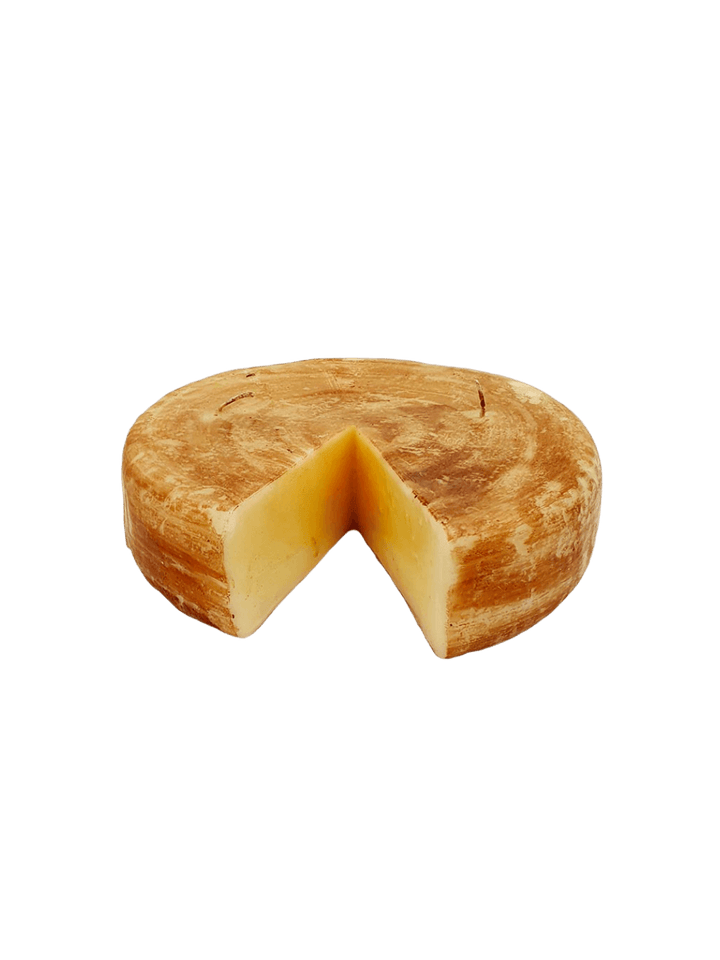 Cheese wheel shaped candle from Cereria Introna with a wedge cut out on a transparent background | Twentyseven Toronto