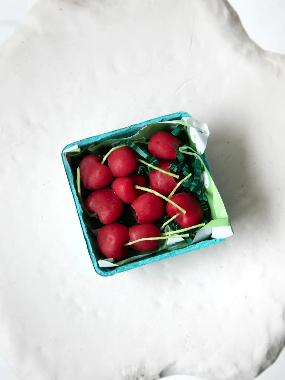 Red cherry-shaped beeswax candles from Happy Organics in a box on a table | Twentyseven Toronto