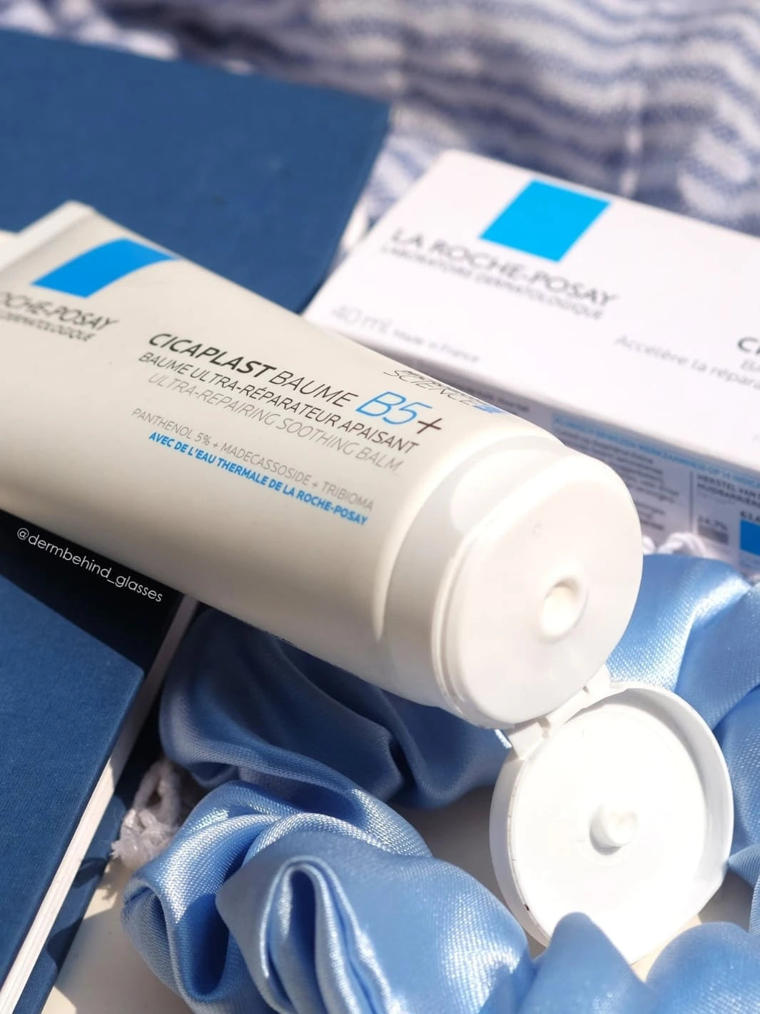 Open tube of La Roche-Posay Cicaplast Baume B5+ Ultra Soothing Cream 100ml on a blue fabric background | Twentyseven Toronto
