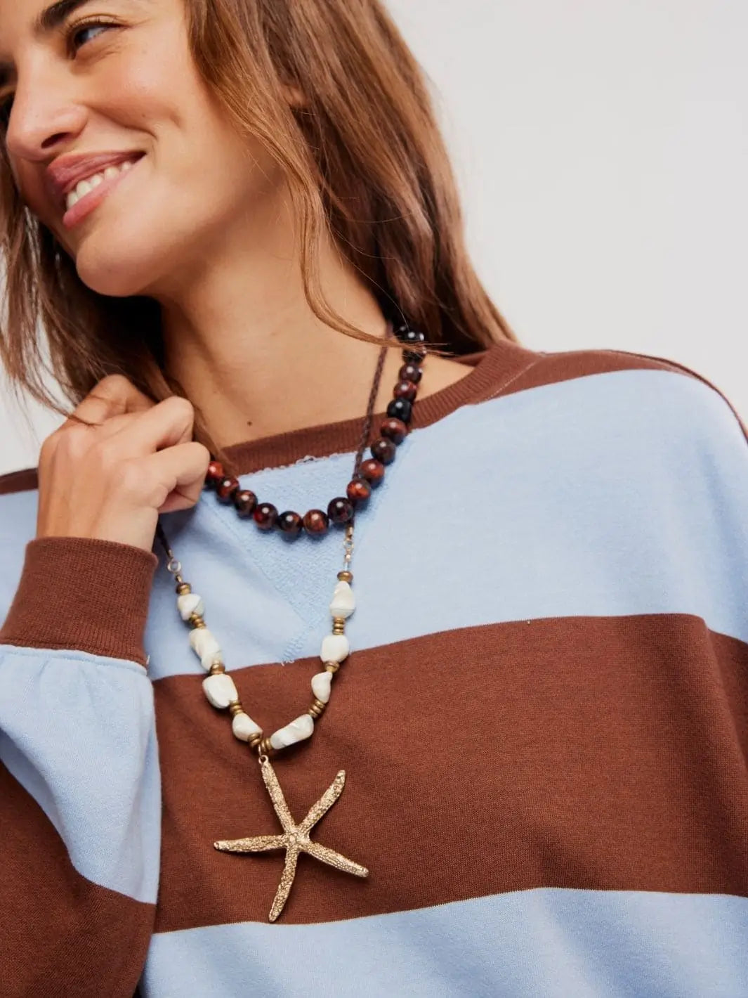 A detailed close-up focuses on the ribbed crew neckline, layered necklaces, and soft knit texture of the Free People Classic Stripe Crew Wide in Periwinkle Combo | Twentyseven Toronto