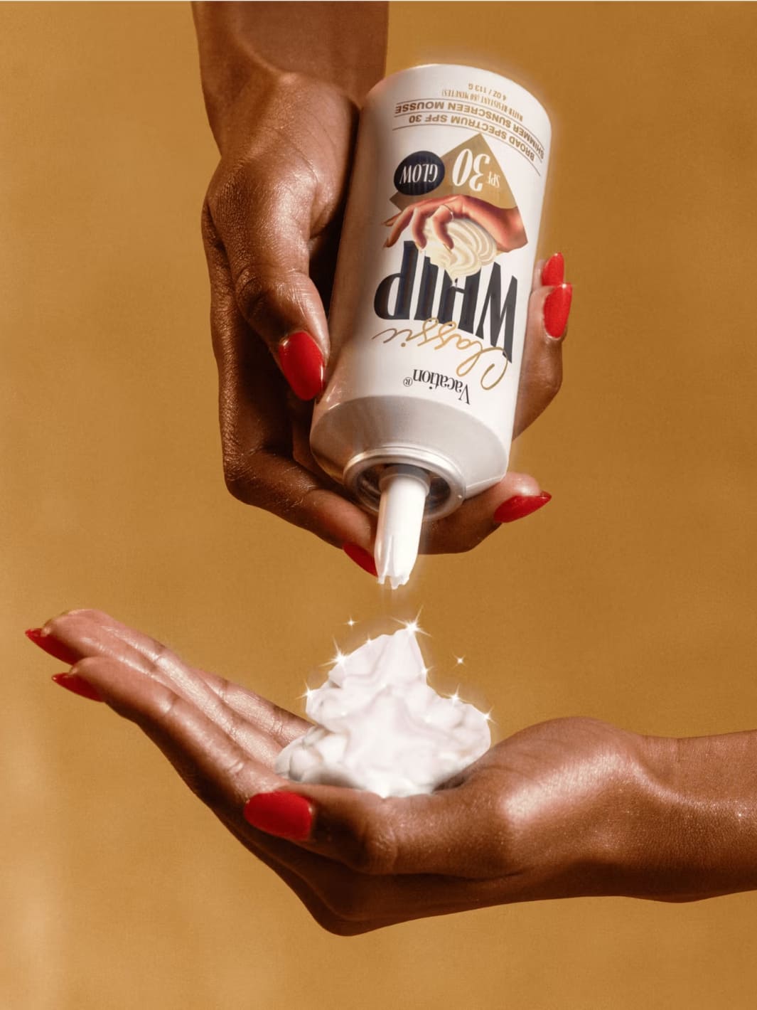 Vacation Inc. Classic Whip Glow SPF 30 | Twentyseven Toronto | Hand holding a tube of Dill M Whipped Soap with soap being dispensed onto another hand against a brown background