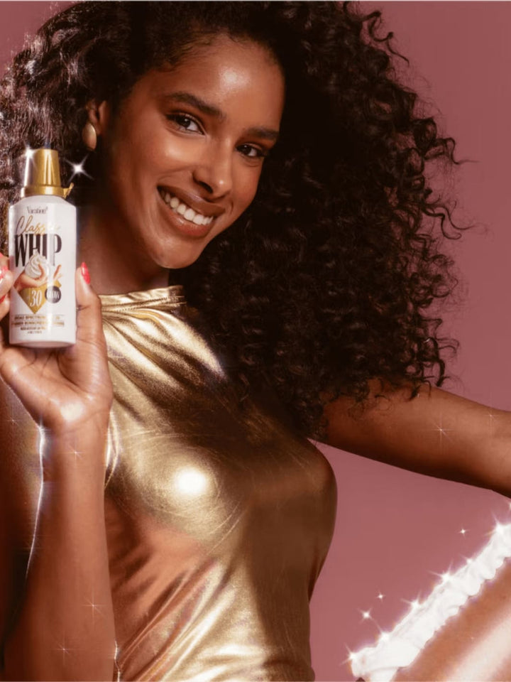 Vacation Inc. Classic Whip Glow SPF 30 | Twentyseven Toronto | Woman holding a bottle of hair product with a sparkly background