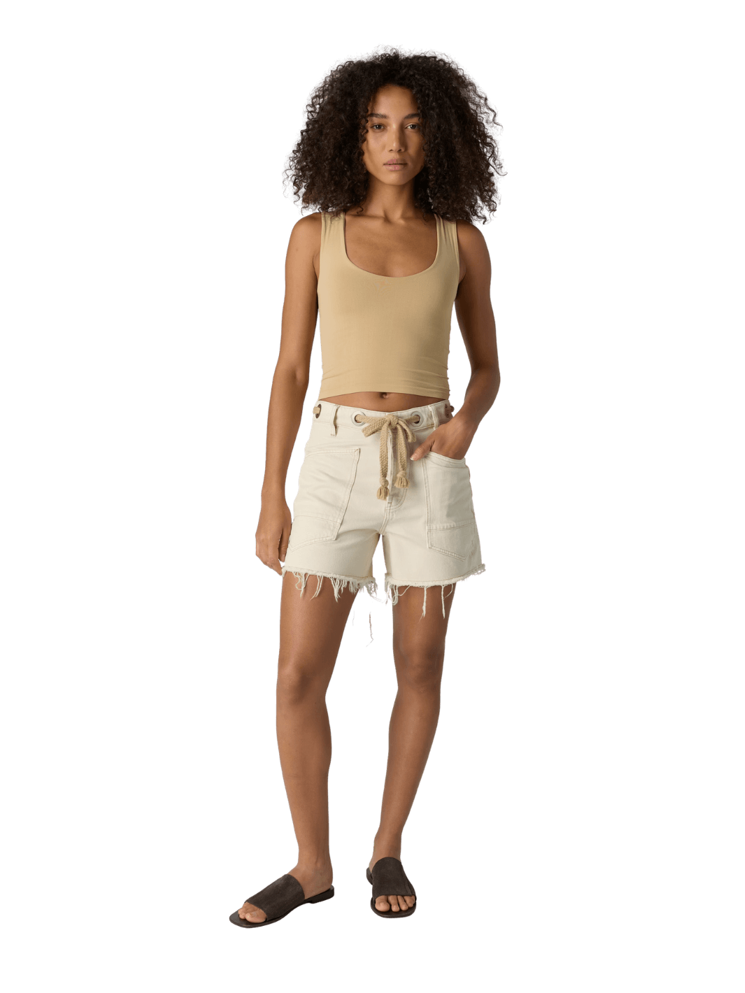 Woman with curly hair wearing a beige 'Clean Lines Muscle Cami' fitted top in 'Oat Latte' from Free People on a transparent background | Twentyseven Toronto