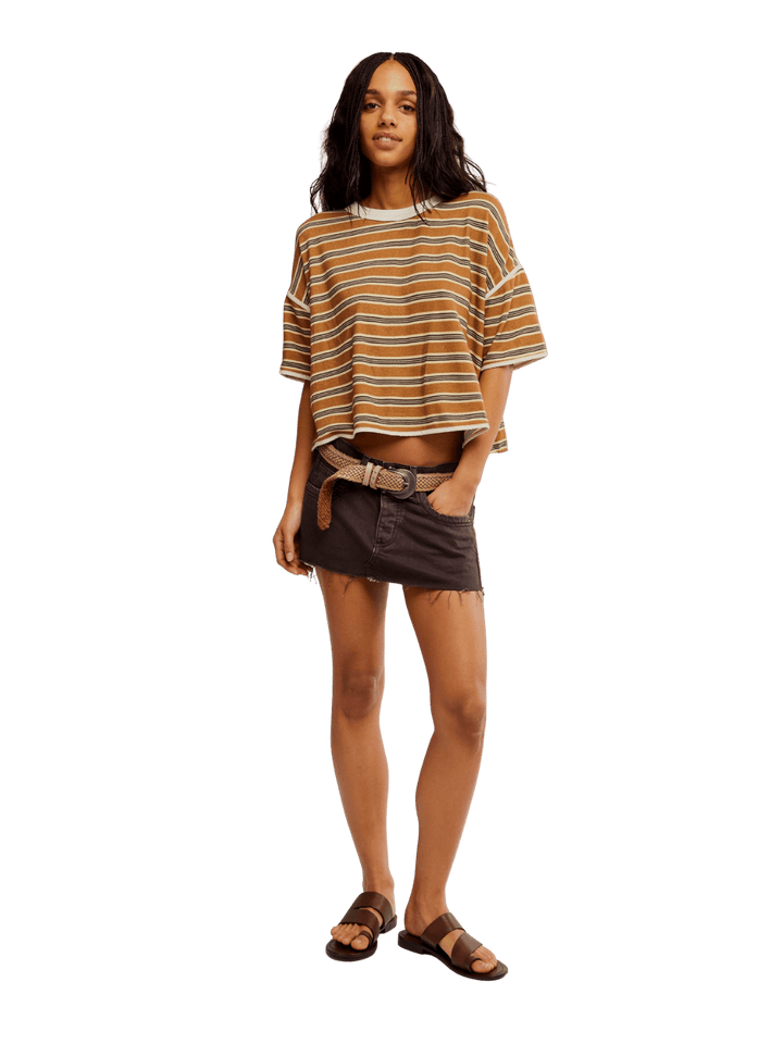 A model dressed in the Free People Clean Rugby Tee in Almond Combo, a brown denim mini skirt, and leather sandals | Twentyseven Toronto