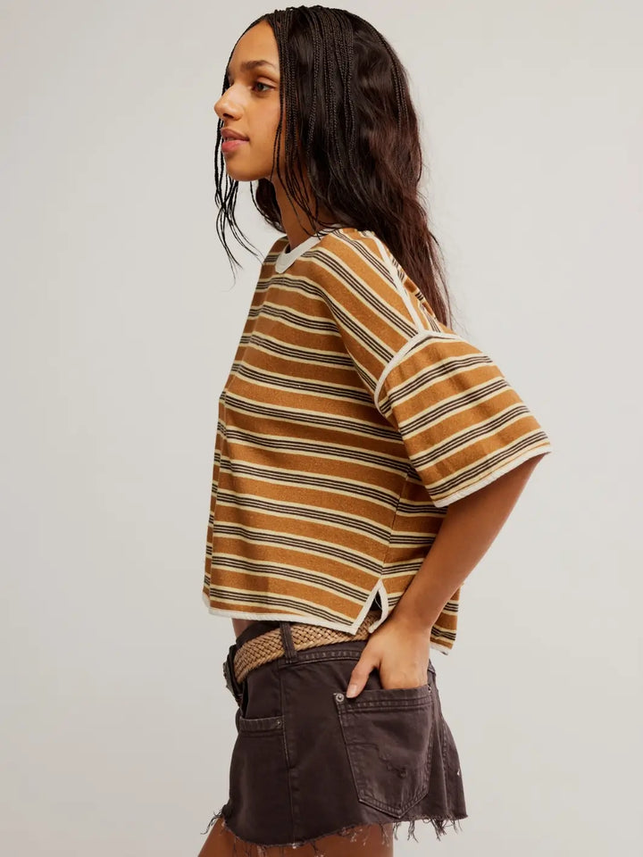 A side profile view of a model standing with her hand in her pocket, highlighting the relaxed fit and short sleeve length of the Free People Clean Rugby Tee in Almond Combo | Twentyseven Toronto