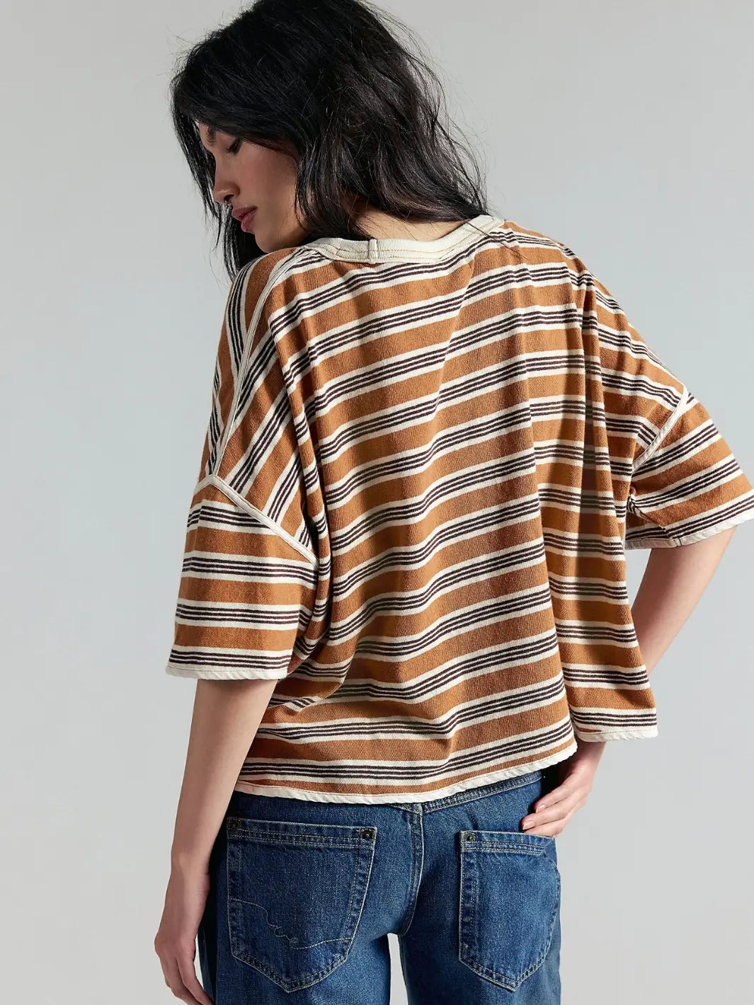 A rear three-quarter view of a model showcasing the back and shoulder construction of the Free People Clean Rugby Tee in Almond Combo | Twentyseven Toronto