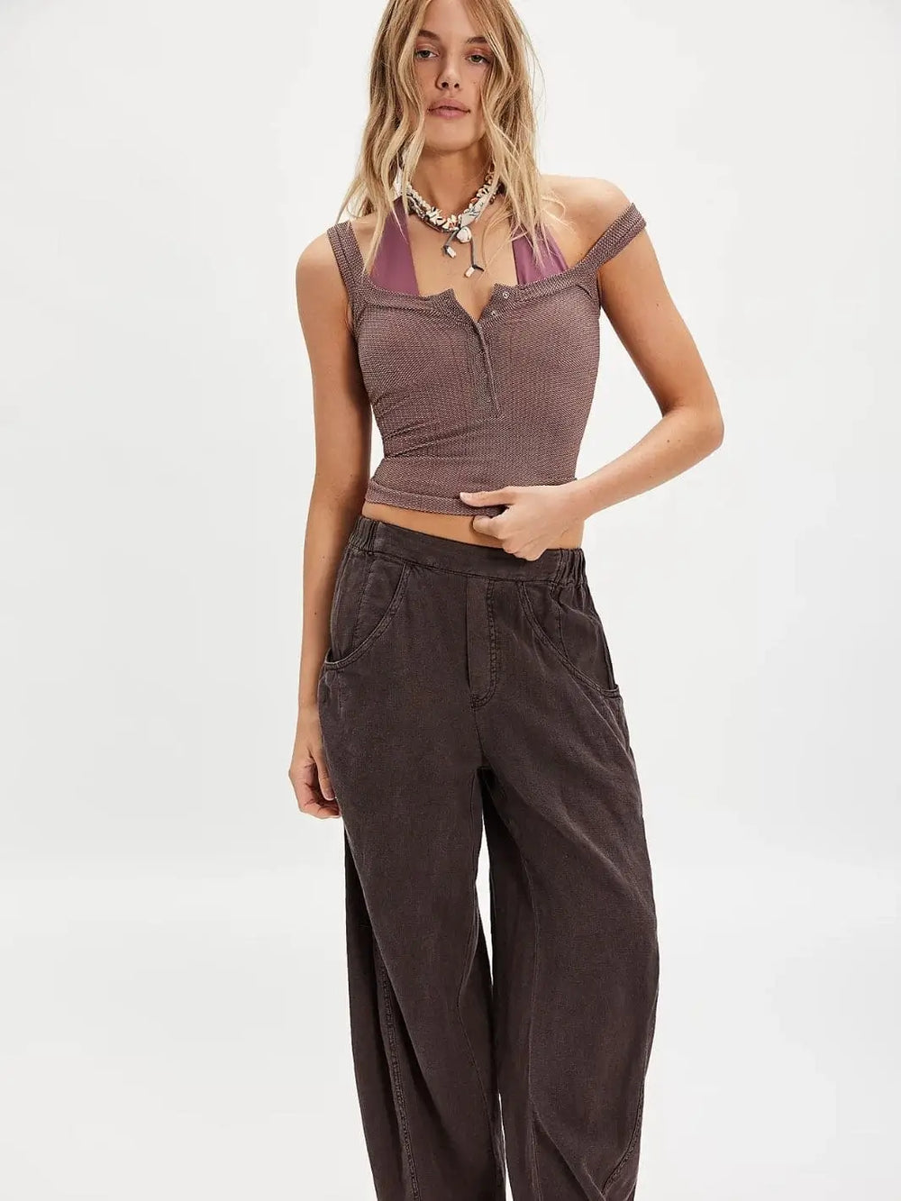 A model stands facing forward wearing the fitted, textured Free People Clean Slate Henley - Mink paired with dark wide-leg trousers | Twentyseven Toronto