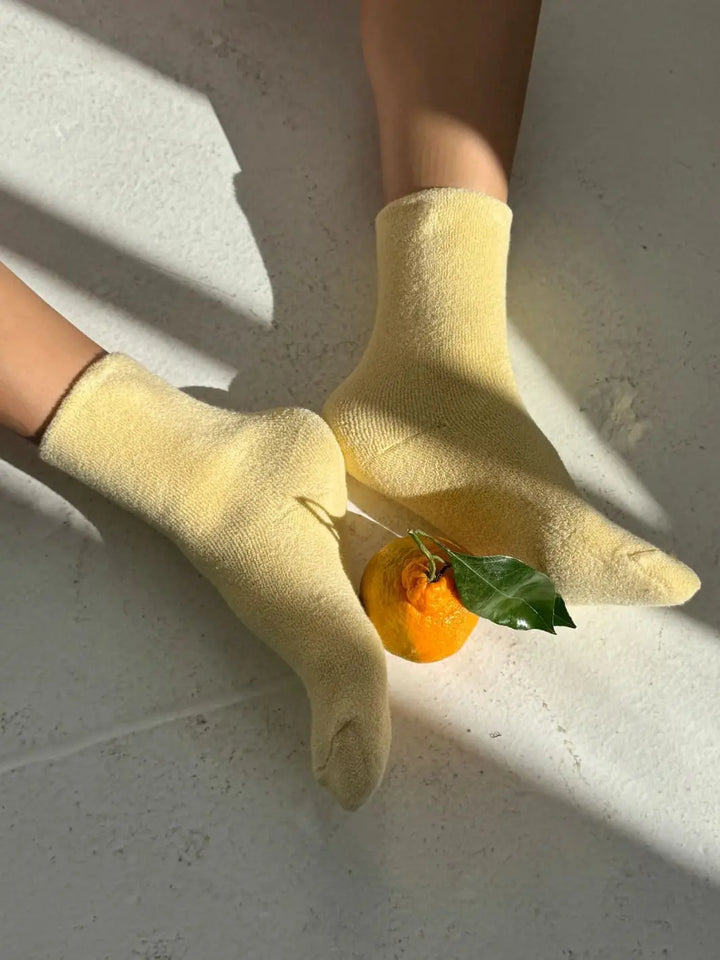 Yellow Cloud Socks in 'Lemon Water' from Le Bon Shoppe with orange fruit inbetween feet | Twentyseven Toronto
