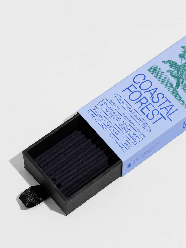 Close-up of Oddly Specific Coastal Forest Low Smoke Incense showing black incense sticks in a pull-out tray and light blue packaging with sandalwood, forest mist and cedarwood scent notes | Twentyseven Toronto