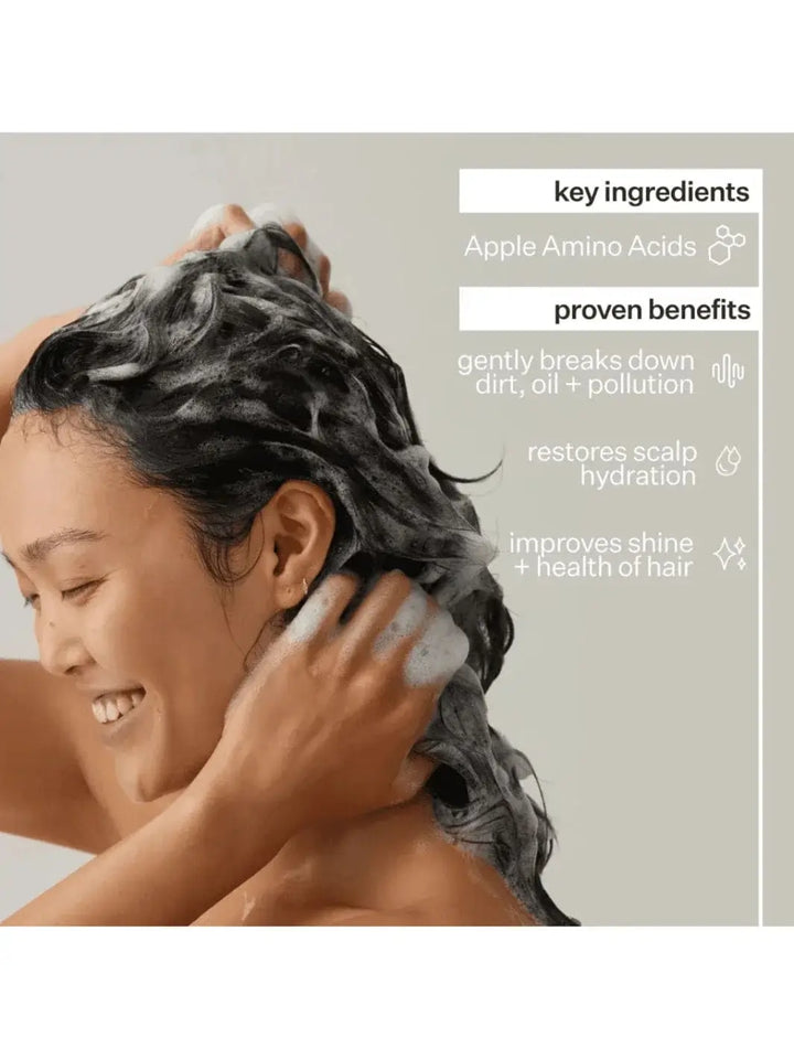 Person washing hair with Act+Acre Cold Processed Shampoo and Conditioner with a focus on key ingredients and proven benefits displayed on the right | Twentyseven Toronto