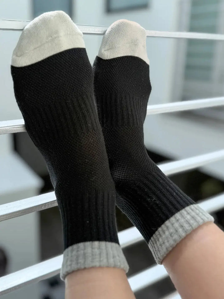 Black 'Color Block Girlfriend Socks' with gray accents and toes in 'Black Grey' style from Le Bon Shoppe on a metal railing | Twentyseven Toronto