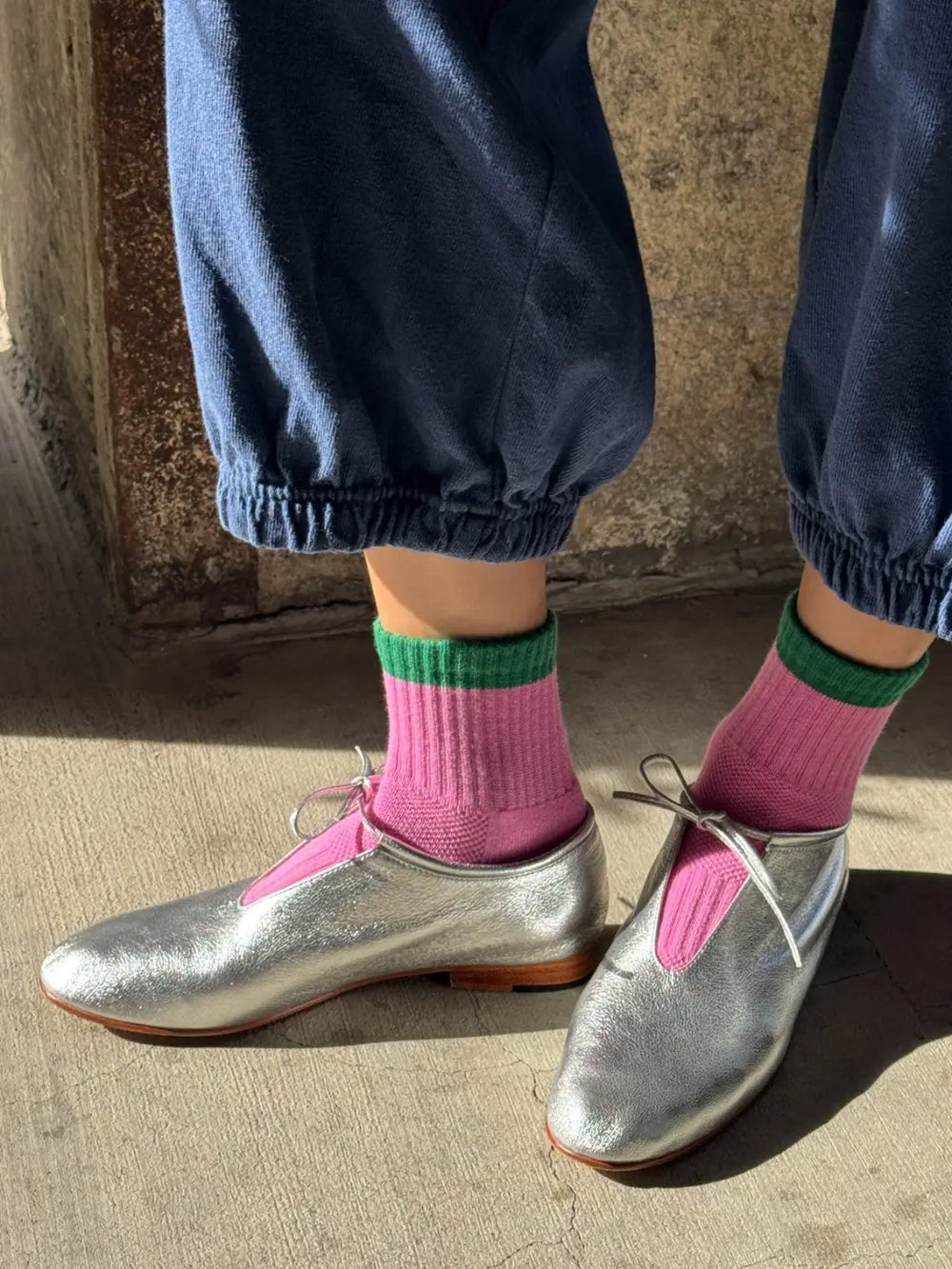 A person standing on a concrete floor wearing metallic silver lace-up oxfords paired with the vibrant Color Block Girlfriend Socks in Rose Green from Le Bon Shoppe | Twentyseven Toronto
