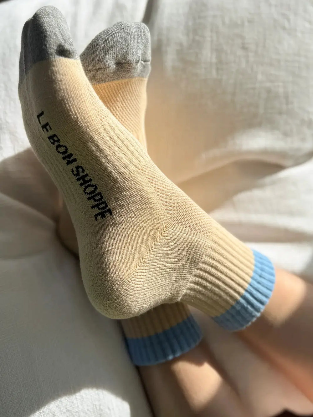 Yellow 'Color Block Girlfriend Socks' in 'Yellow Blue' style from Le Bon Shoppe with gray toes and sky blue accents on a bed | Twentyseven Toronto
