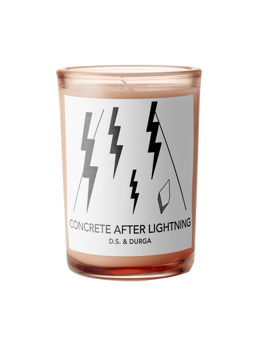 DS&Durga candle in an orange glass jar labeled 'Concrete After Lightning' featuring lightning bolt designs on a transparent background | Twentyseven Toronto