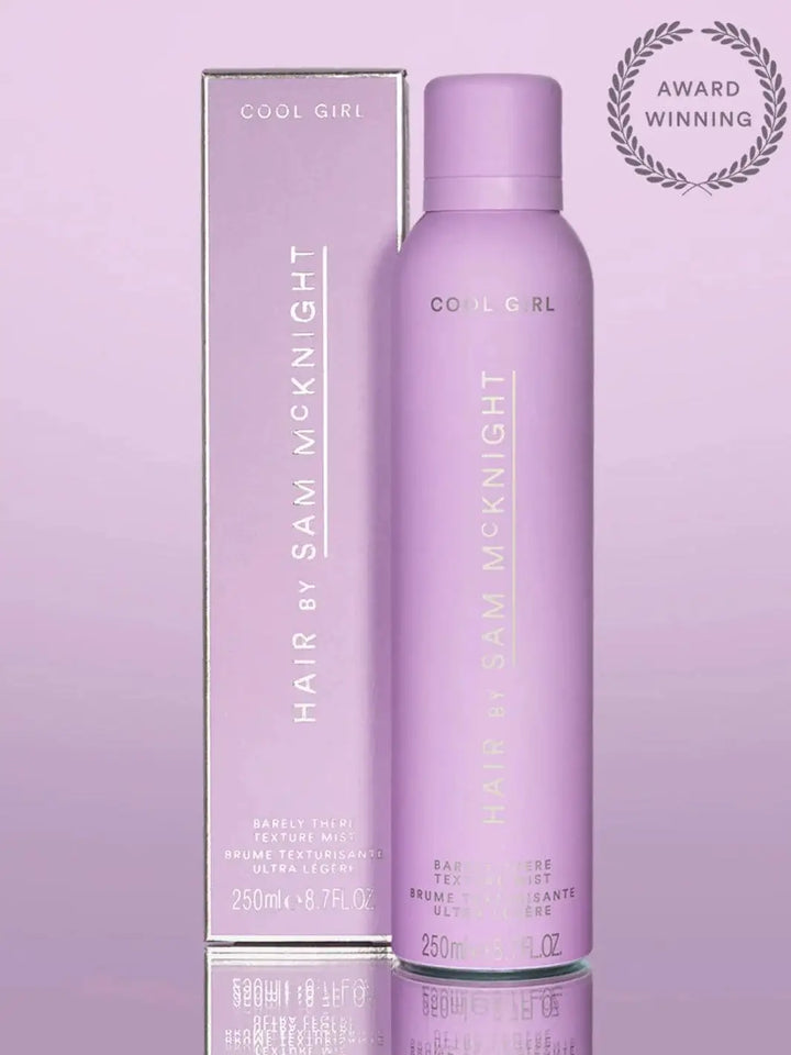 A light pink aerosol can stands in front of its matching product box to display the award-winning packaging of Hair by Sam McKnight Cool Girl Barely There Texture Spray | Twentyseven Toronto