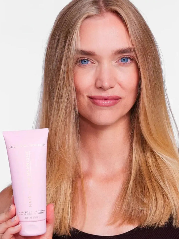 A close-up portrait shows a model with full, healthy blonde hair holding up the tube of Hair by Sam McKnight Cool Girl Volume Conditioner | Twentyseven Toronto
